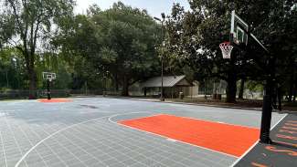 a lined outdoor basketball court with gray and orange tiles