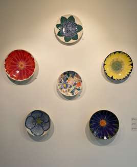 brightly colored ceramic plates hung on a gallery wall.