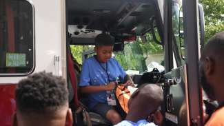 Camper sitting inside fire truck with other campers waiting their turn