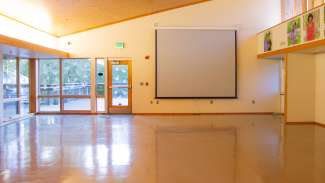 A large open room with lots of windows and a pull-down projector 