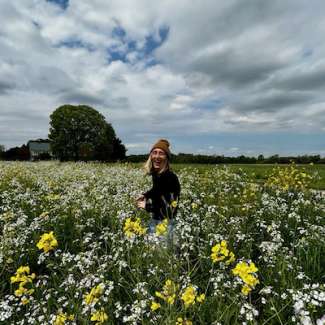 Photo of artist standing in a field of flowers