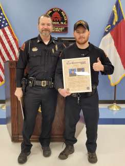 Officer Vanderhoof receives his plaque. NC and American flag and podium in the background